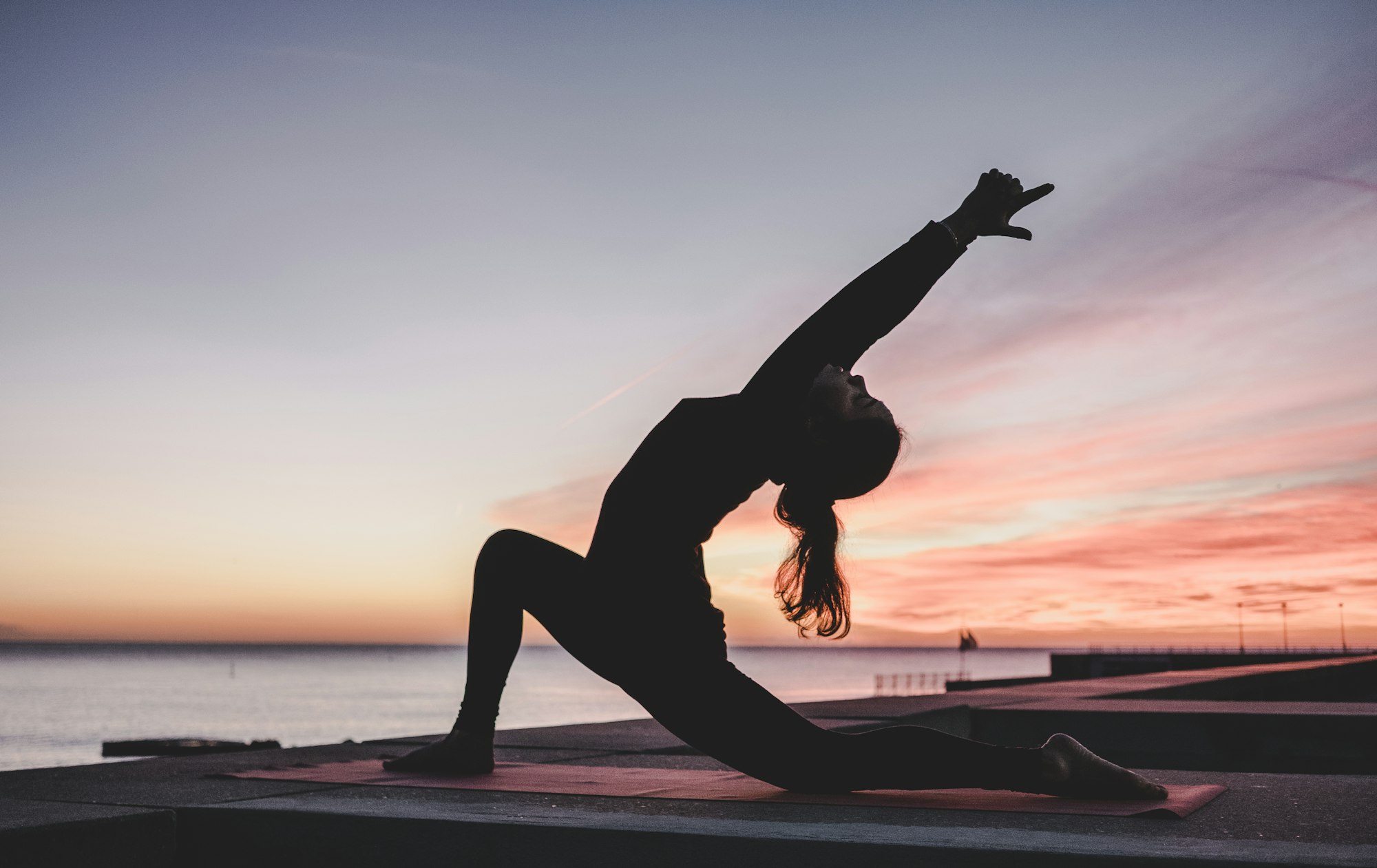 Mulher praticando yoga ao ar livre durante o pôr do sol